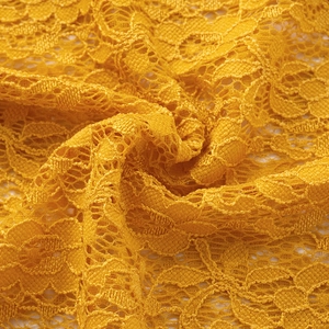 Gros plan sur un tissu en dentelle jaune vif montrant des motifs floraux ajourés