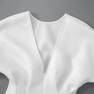 Detailed view of white V-neck dress featuring elegant waist pleats and premium fabric texture