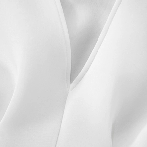 Detail of the white chiffon fabric texture and V-neckline on the waist-cinched mini dress