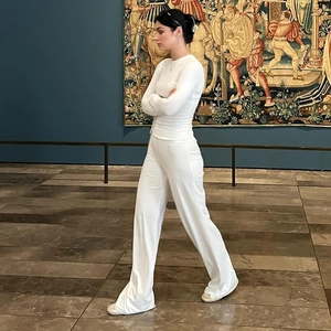 Elegant white long sleeve top and wide leg pants set shown in a classic museum interior