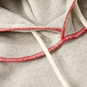 Close-up of light grey hoodie with red overlock stitching and white drawstring detail