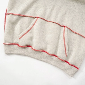 Detail of grey hoodie showing contrast red stitching on kangaroo pocket and ribbed hem