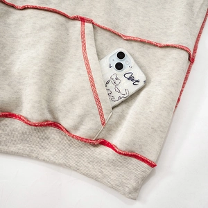 Close-up of casual grey hoodie pocket with contrasting red stitching and soft texture
