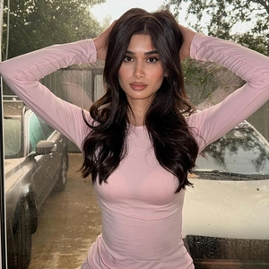 Detail of pink slim fit long sleeve crew neck top with elastic fabric on model