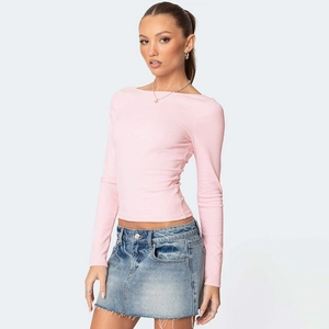 Close-up detail of a slim-fit long sleeve pink knit top paired with a denim skirt