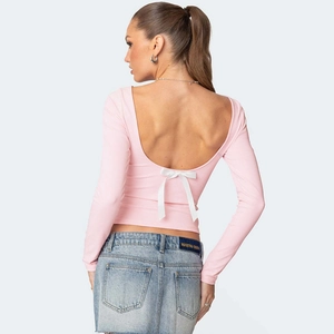 Detail of light pink long sleeve top with backless design and white decorative bow