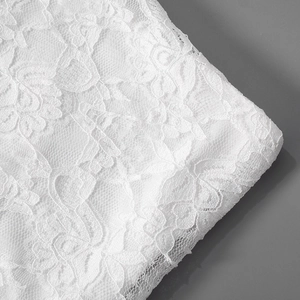 Close-up of white floral lace embroidery with detailed mesh pattern for elegant dresses