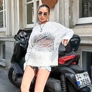 Detail of white oversized distressed knit sweater with openwork mesh and ripped accents