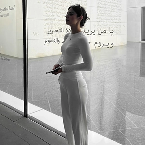 Detail view of white long sleeve knit top and high-waisted wide-leg trousers set