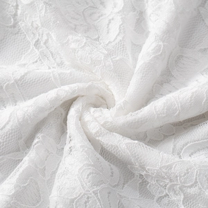 Close-up of white lace fabric with intricate floral embroidery and jagged lace edges