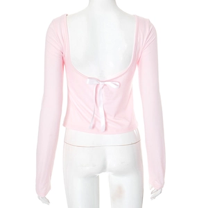 Detail of pink long sleeve crop top featuring a deep open back and a satin white bow