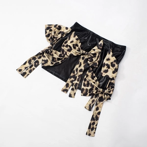 Dettaglio della gonna in similpelle nera con grandi fiocchi con stampa leopardata
