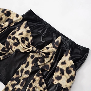 Dettaglio gonna in pelle lucida con fiocco leopardato e volant decorativi chic