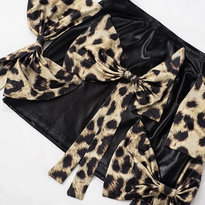 Dettaglio della minigonna in pelle nera con grandi fiocchi con stampa leopardata alla moda