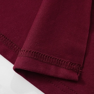 Detailaufnahme der Doppelnaht am Saum und der Overlock-Stiche auf dunkelrotem Strick