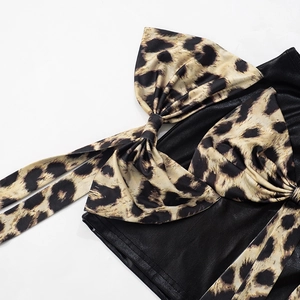 Dettaglio del fiocco leopardato su gonna in pelle nera con cuciture di precisione
