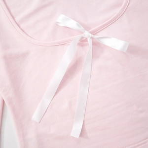 Detail view of pink long sleeve top with a delicate white satin bow on the neckline