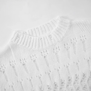 Detail of white knit sweater showing distressed round neckline and hollow-out texture