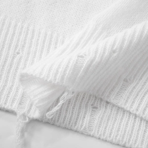 Close-up of white knit sweater showing ribbed texture and distressed cutout details