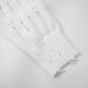 Close-up of white distressed knit sweater cuffs featuring hollow wave texture and fringes