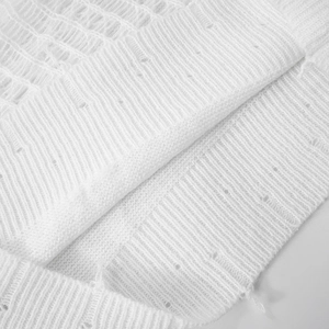 Close-up of white knit sweater showing hollow-out texture and stylish distressed details