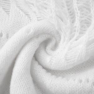 Detailed close-up of pure white hollow crochet knit fabric with elegant texture