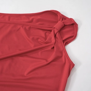 Détail d'une robe moulante rouge avec un nœud à l'épaule et des plis de tissu élégants