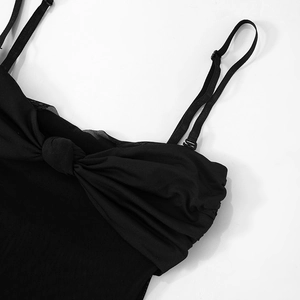 Détail de la robe noire avec fines bretelles réglables et nœud torsadé sur la poitrine