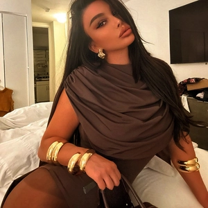 Close-up of chunky gold polished bracelets and irregular earrings on a model
