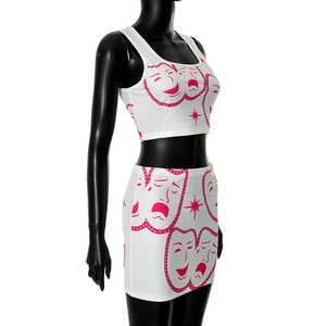 Detail of white two-piece set featuring pink comedy and tragedy mask prints on tight mini skirt