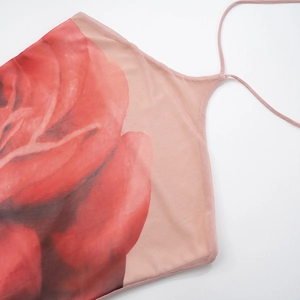 Dettaglio dell'abito rosa allacciato al collo con stampa di rose rosse e spalline