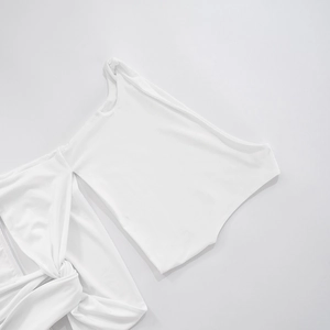 Macro shot of the knot design and irregular cutout details on the white mini dress