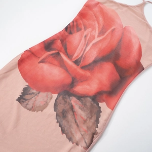 Dettaglio della stampa floreale con rose rosse sul vestito lungo rosa con scollo a cavezza