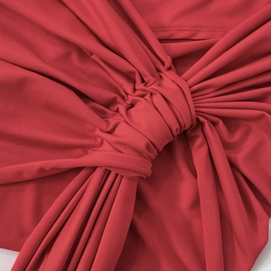 Vue macro détaillée de la texture froncée et du nœud torsadé sur la robe rouge moulante
