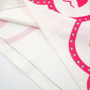 Detailed close-up of ribbed knit fabric texture with pink heart print and overlook stitching