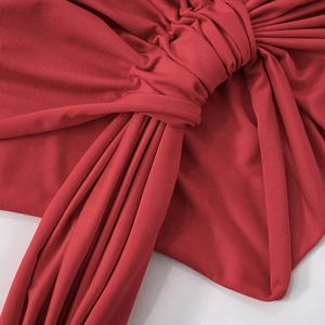 Détail macro du design à nœud et de la texture plissée sur une robe courte rouge