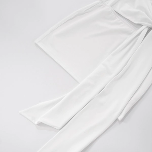 Detailed close-up of ivory white knitted dress with long decorative lacing and flat seams