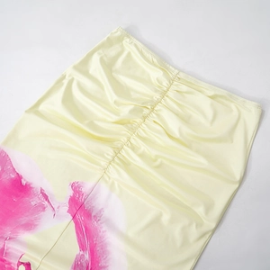 Detail of elegant yellow satin skirt featuring ruched center design and pink floral print