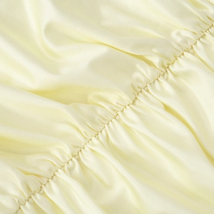 Close-up detail of cream floral satin fabric with elegant shirred and gathered textures