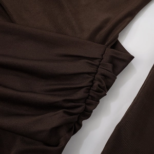 Detail view of ruched dark brown knitted fabric texture with fine ribbing for a dress