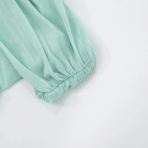 Close-up of mint green mesh fabric with elastic ruffled cuffs on a slim maxi dress