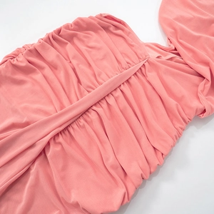 Close-up of pink ruched knit dress showing elastic pleated fabric and textured layering