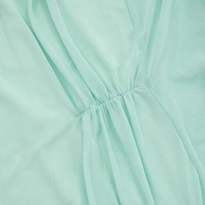 Detailed close-up of pleated mesh fabric on a light mint green strapless maxi dress