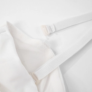 Détail d'une bretelle réglable et d'un crochet en plastique sur robe en maille blanche