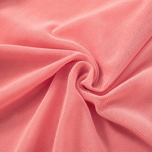 Macro detail of breathable coral pink mesh fabric with elegant pleated texture and soft drape