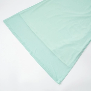 Detail of light mint green dress showing layered hem design and premium knit fabric