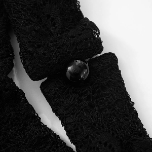 Close-up of intricate black floral lace pattern with a glossy button detail on summer dress