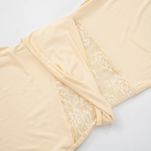 Detailed view of champagne dress featuring white floral lace patchwork and waist twist design