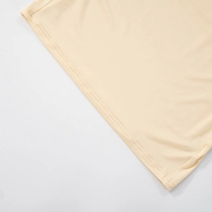Detailed macro view of the double-needle stitched hem on light beige summer dress fabric