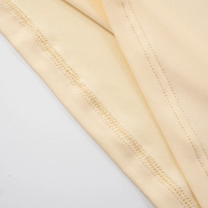 Detailed macro shot of fine ribbed texture and double needle stitching on beige dress